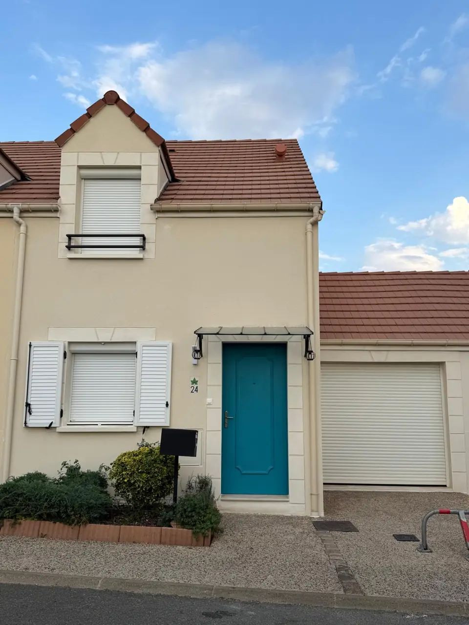 Façade claire rénovée, avec sa porte bleue et ses ouvertures.