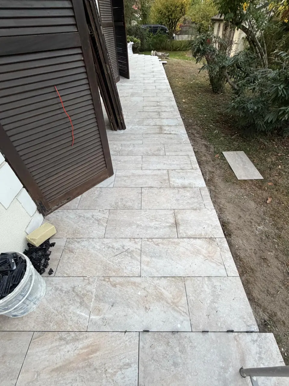 Terrasse et marches en pierre claire au pied d’une maison.