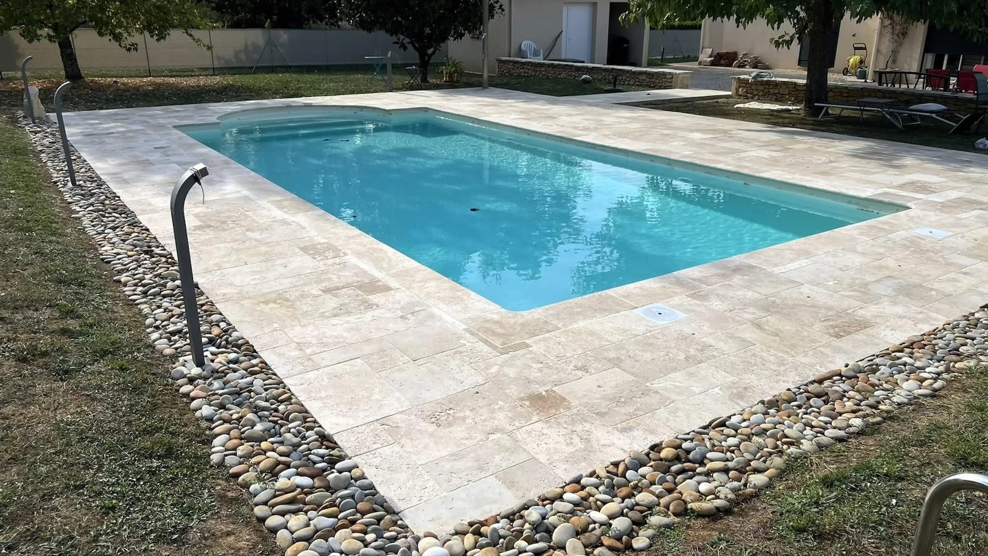 Piscine entourée d’un dallage clair et d’une bordure de galets.